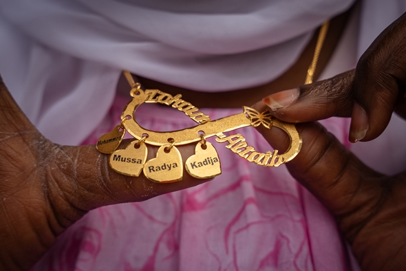 Mor viser fram smykke med namna på barna