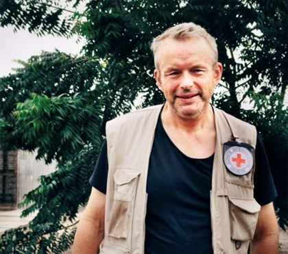 Mann i beige vest med røde kors logo