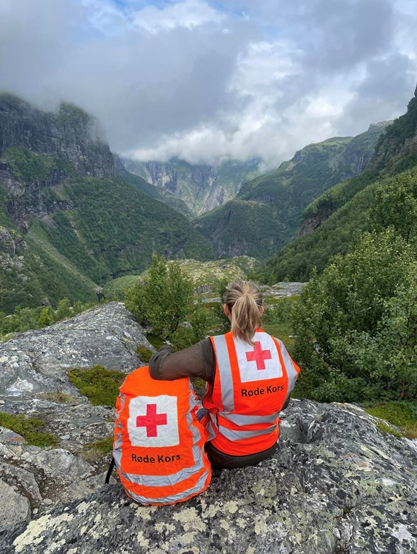 Kvinne med Røde Kors vest i vakkert dal-landskap