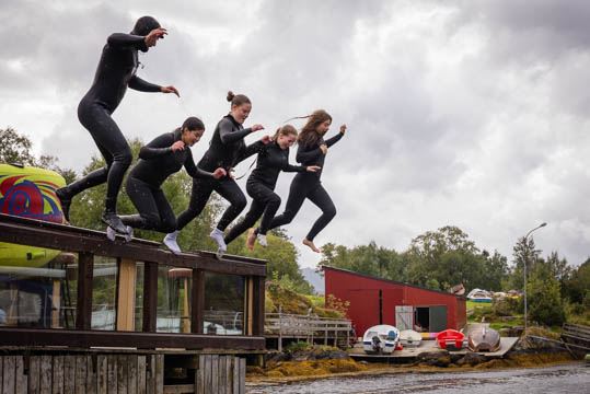 Gruppe i oransje vestar hjelper mann som ligg i båre. 