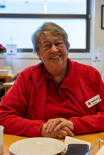 Astri sit ved eit bord og smiler til kamera