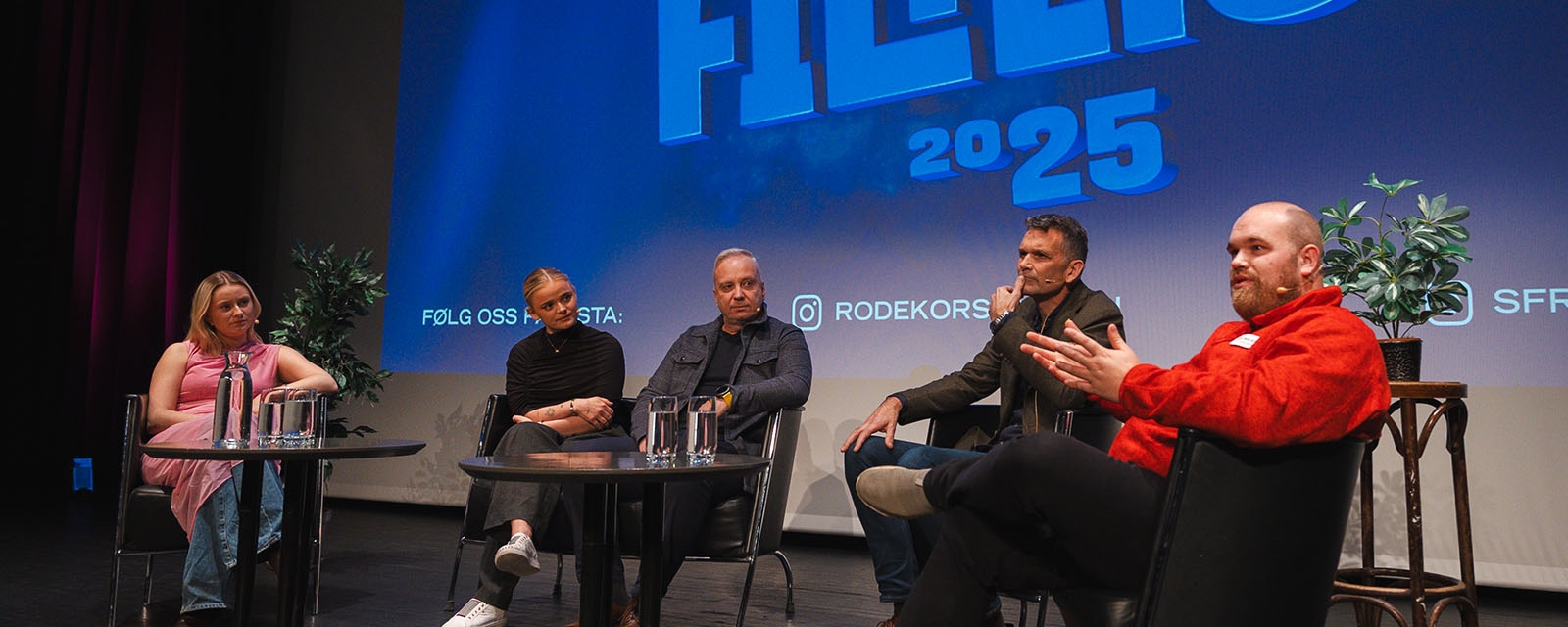 To kvinner, og tre menn sit og pratar på scena.