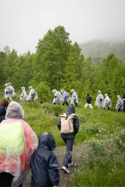 Menneske går på veg oppover mot Fagreggi i kvite regnponchoer.