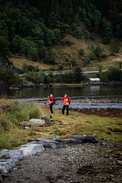 To frivillige går langs vatnet og søker.