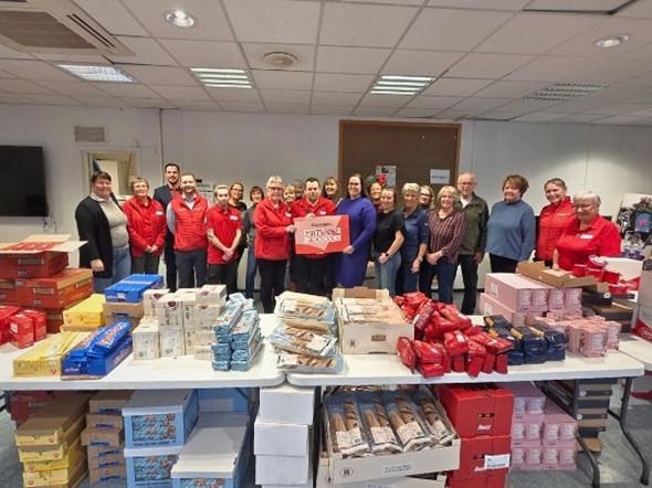 Ein stor gjeng med frivillige held opp ein sjekk som står 200.000 kr på.