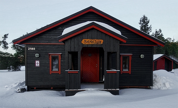 Inngangsparti på trehytte. Snø.