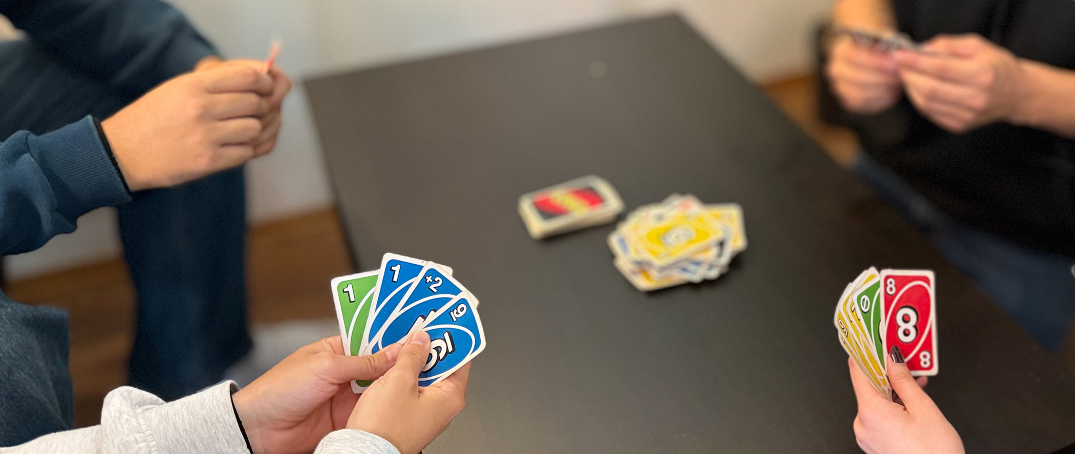 Bilde av hender under Uno kortspill.