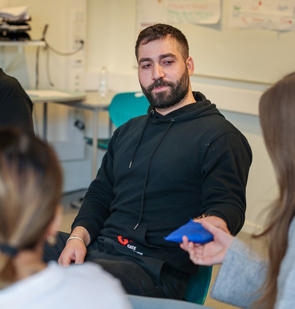 Anas Alammori gir snakkepute videre til elev under workshop, Gatemegling.