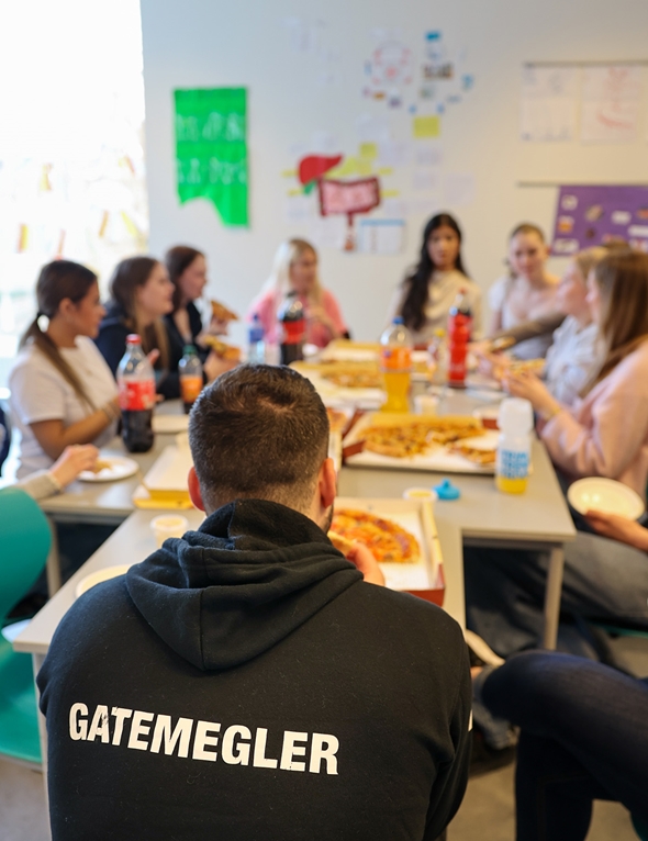 Workshop på skole hvor de sitter samlet å spiser pizza.