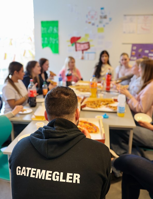 Workshop på skole hvor de sitter samlet å spiser pizza.