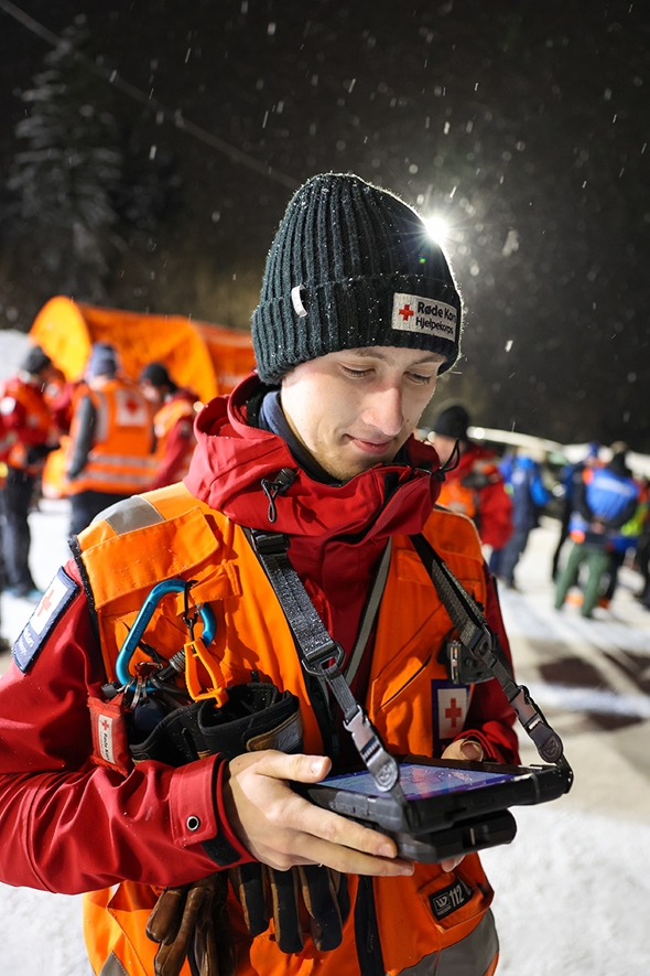 Frivillig fra Hjelpekorpset holder en iPad med det nye systemet FAKS på.