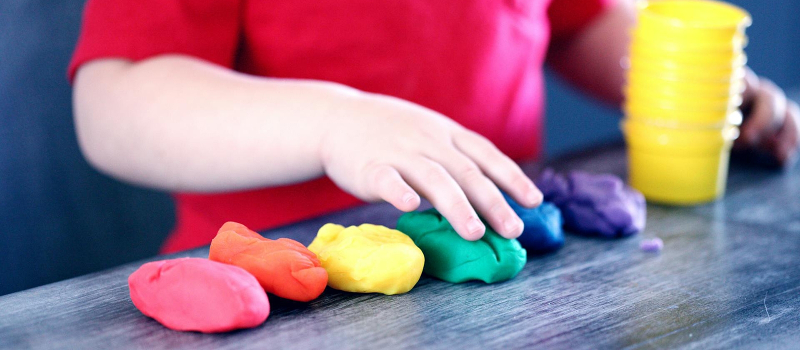 Barnehånd som leker med farget leire.