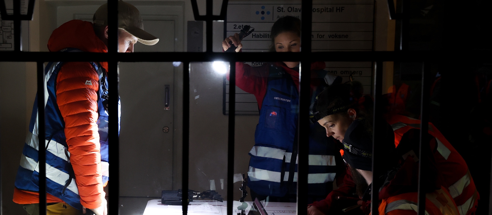 Tre hjelpekorpsere ser på byggetegninger i forbindelse med øvelse i hussøk.