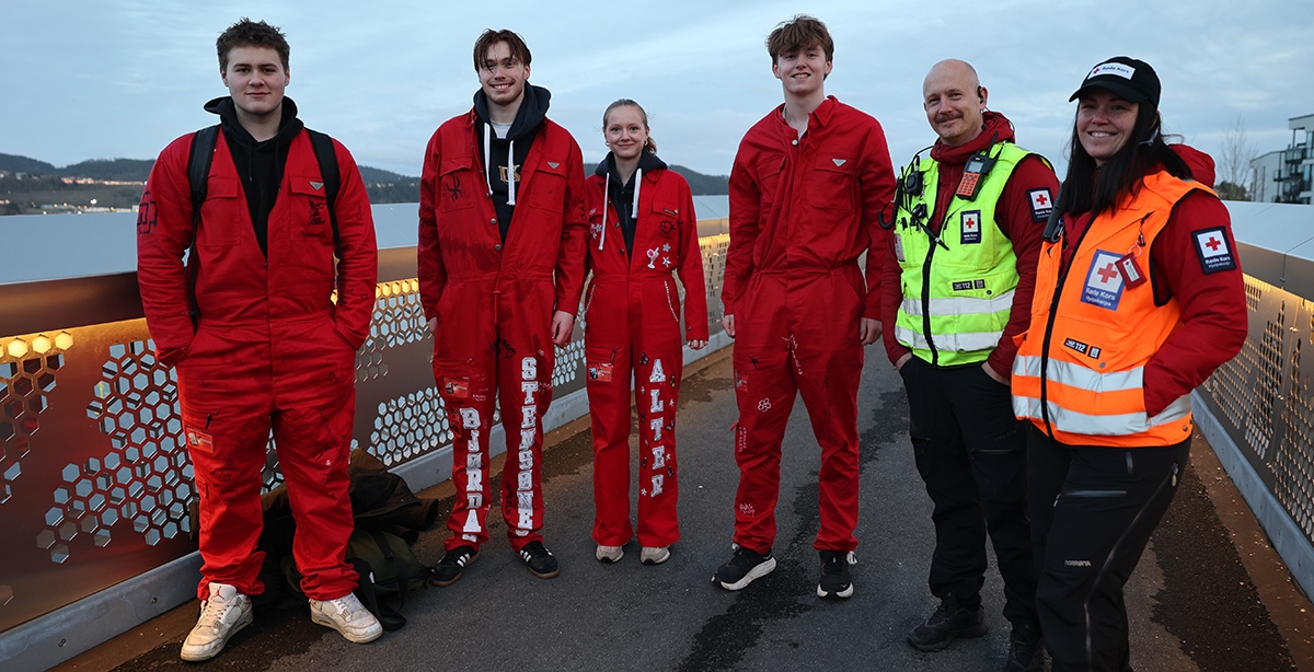 Fire rødruss står på en bro sammen med to frivillige fra Trondheim Røde Kors hjelpekorps.