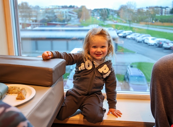 Birk på 3 år sitter å soiser i vinduskarmen under åpningen av Familiesenter Saupstad.