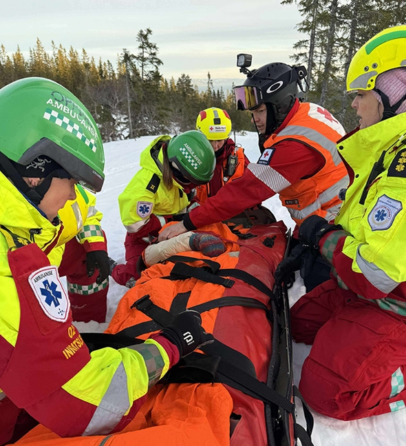 Ambulansepersonell og mannskaper fra Røde Kors samarbeider tett om behandling og trygg forflytning av pasienten.