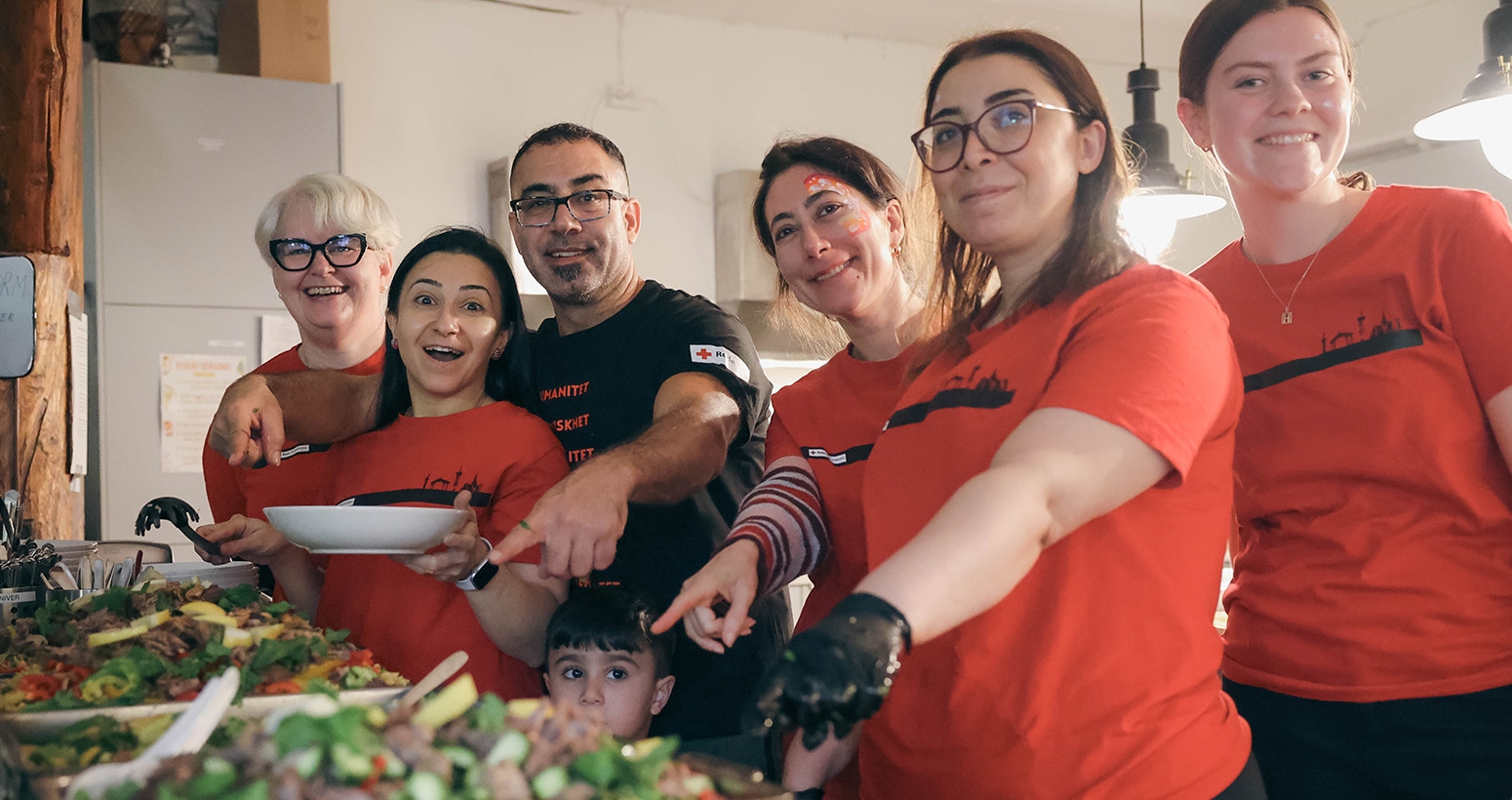 Frivillige på Familiesenteret er smiler og viser frem maten som skal serveres.