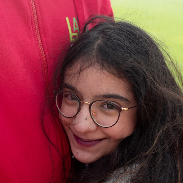 Nærbilde av en jente som koser på noen med en rød genser med Bark-logo. Hun smiler til kamera og har briller.