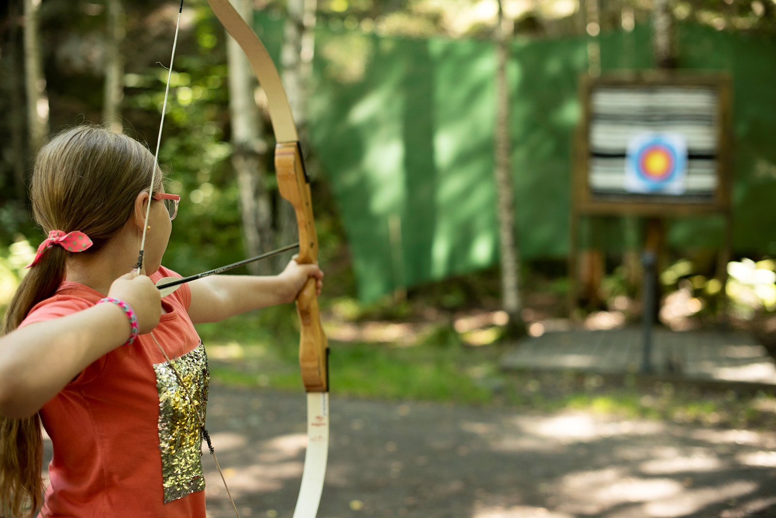 Jente skyter med pil og bue på blink i skogen