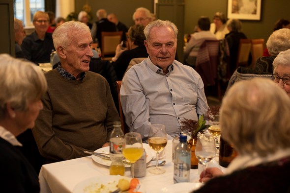 Tre eldre menn sitter rundt et bord