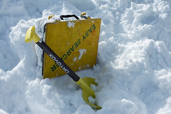 En skredkoffert og en spade står i snøen.