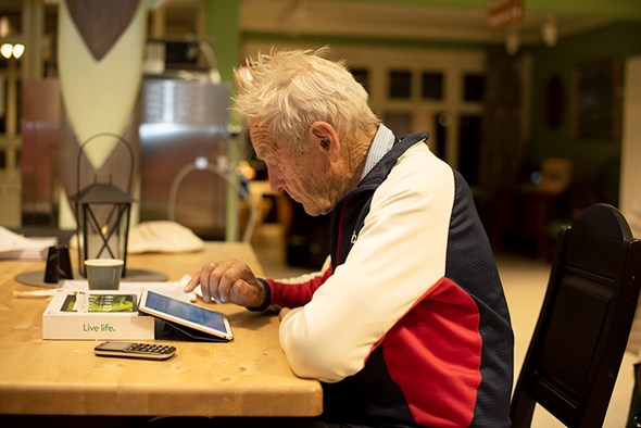 En eldre mann sitter på pad og jobber