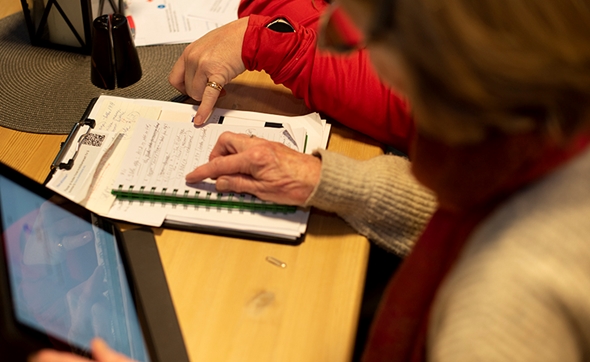 Hender som noterer på en notatblokk