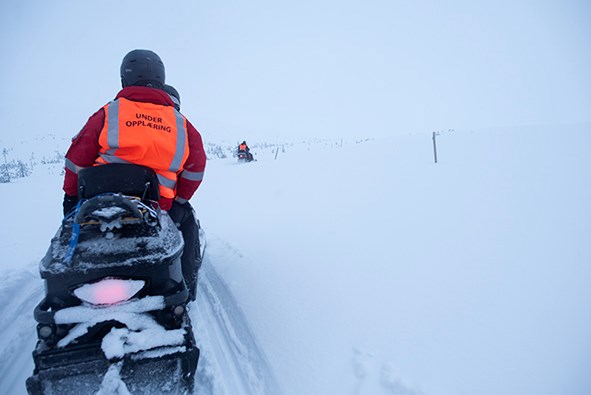 Snøscooter kjører innover vidda en tåkete vinterdag