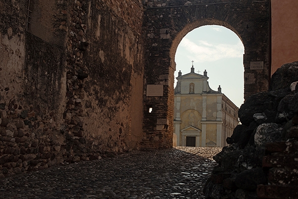 Porten til Solferino - en antikk gammel bygning synes gjennom en buegang i en steinmur