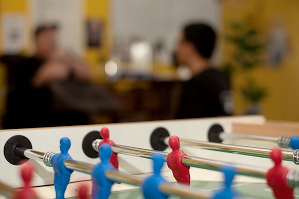 Fussballbord i fokus i forgrunn, i bakgrunnen uklart ser vi to menn som sitter og prater