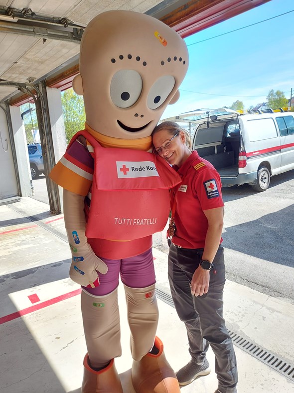 En Henry-dukke gir en klem til en frivillig i Røde Kors-klær.