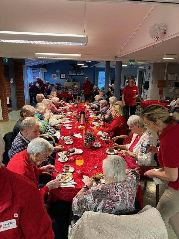 Mange eldre mennesker som sitter i en samlingssal og spiser mat