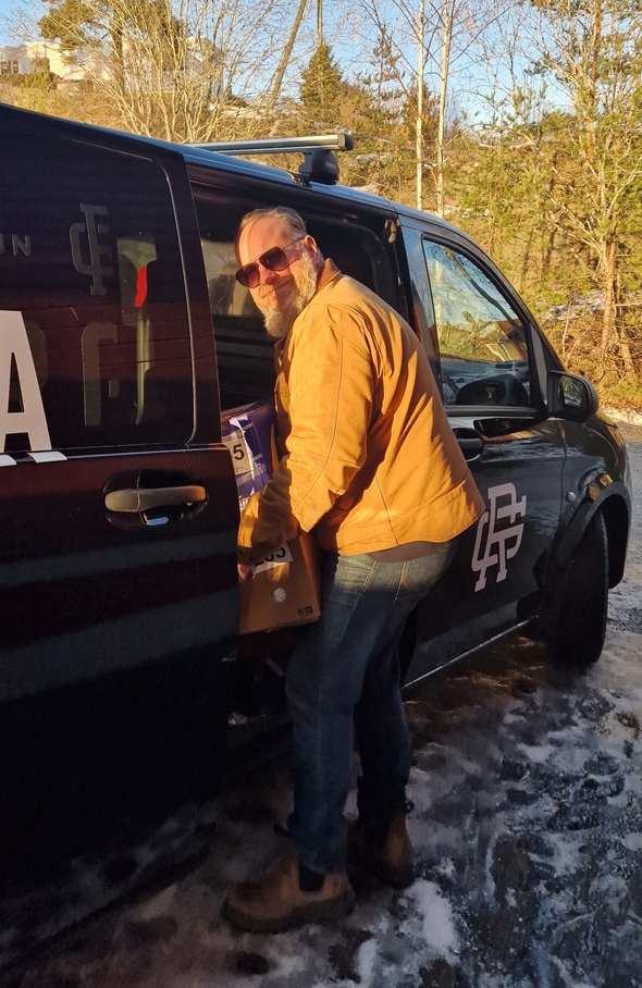 En mann legger en eske inn i en bil