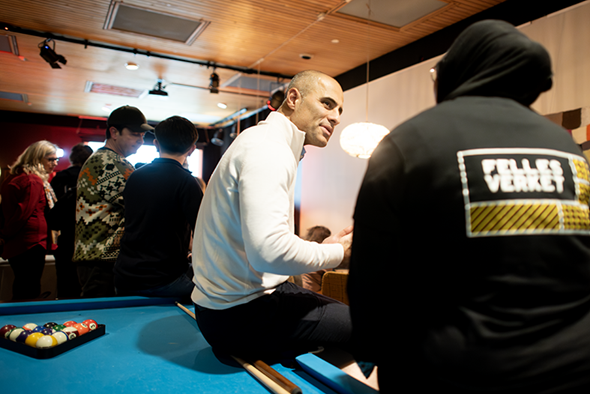 To personer sitter i dyp samtale på et biljardbord