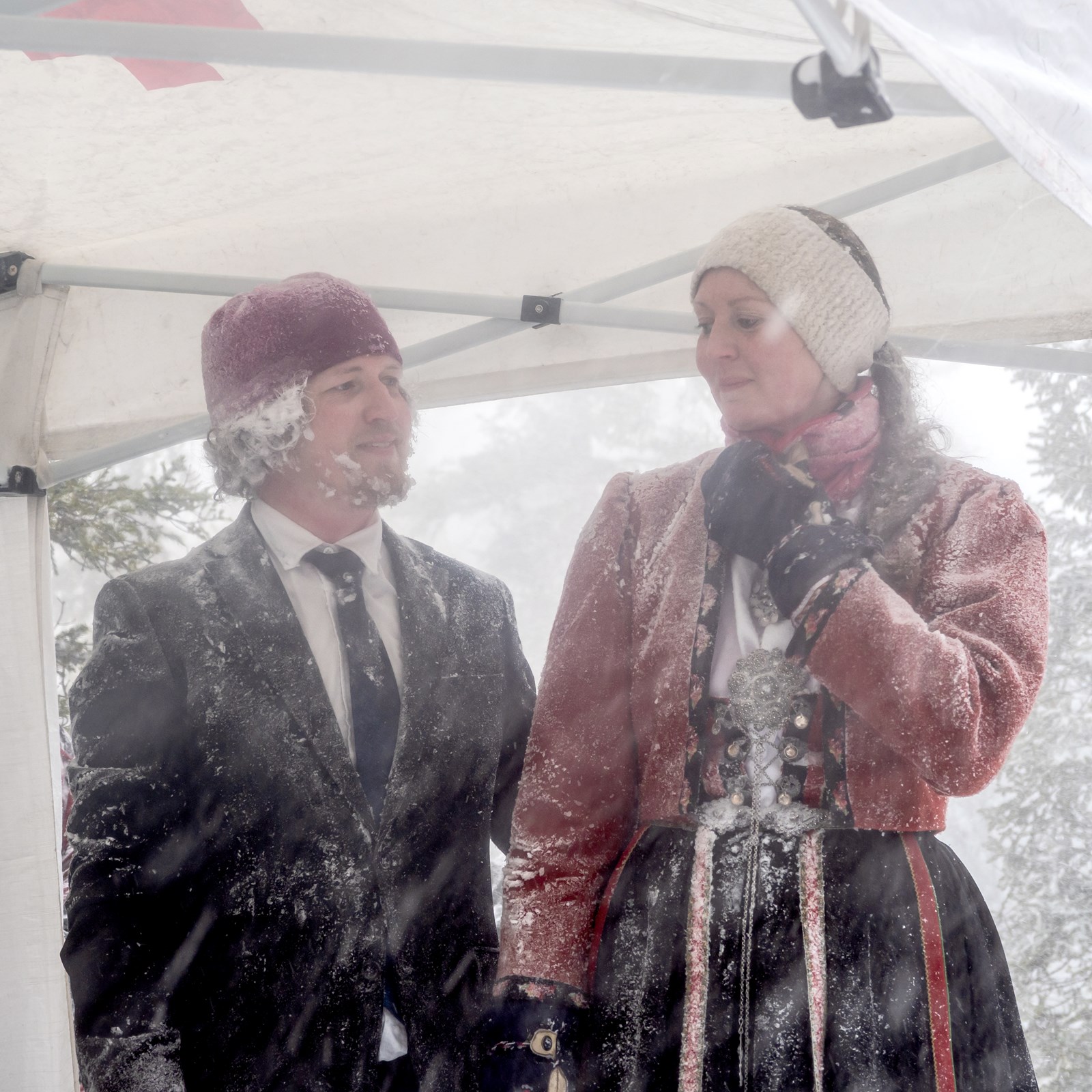Bilde av et par som holder hverandre i hendene under et telt i snøstorm.