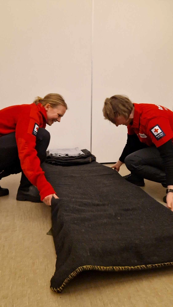 Røde Kors-frivillige rer opp feltseng