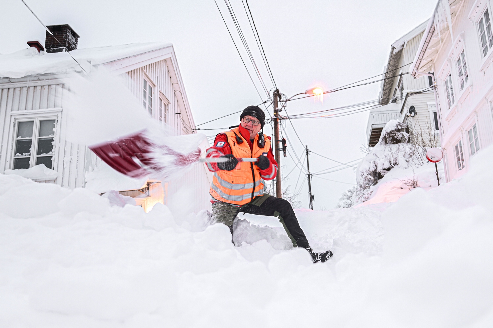 Mann står til knes i snø og måker