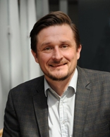 Bilde av mann i lys skjorte og rutete blazer