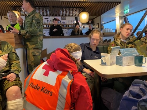 En hjelpekorpser hjelper en skadet person om bord på en båt.