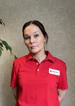 Maria har på seg en rød t-skjorte på med Røde Kors-logo. Hun smiler til kamera.