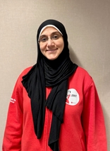 Nihal har på seg en rød genser med Røde Kors-logo. Hun smiler til kamera.