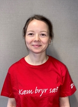 Thea har på seg en rød t-skjorte på med Røde Kors-logo. Hun smiler til kamera.