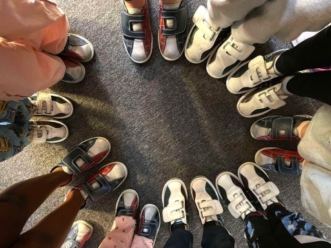 Bildet viser mange barn som har bowlingsko på. De står i en sirkel sammen.