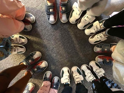 Bildet viser mange barn som har bowlingsko på. De står i en sirkel sammen.