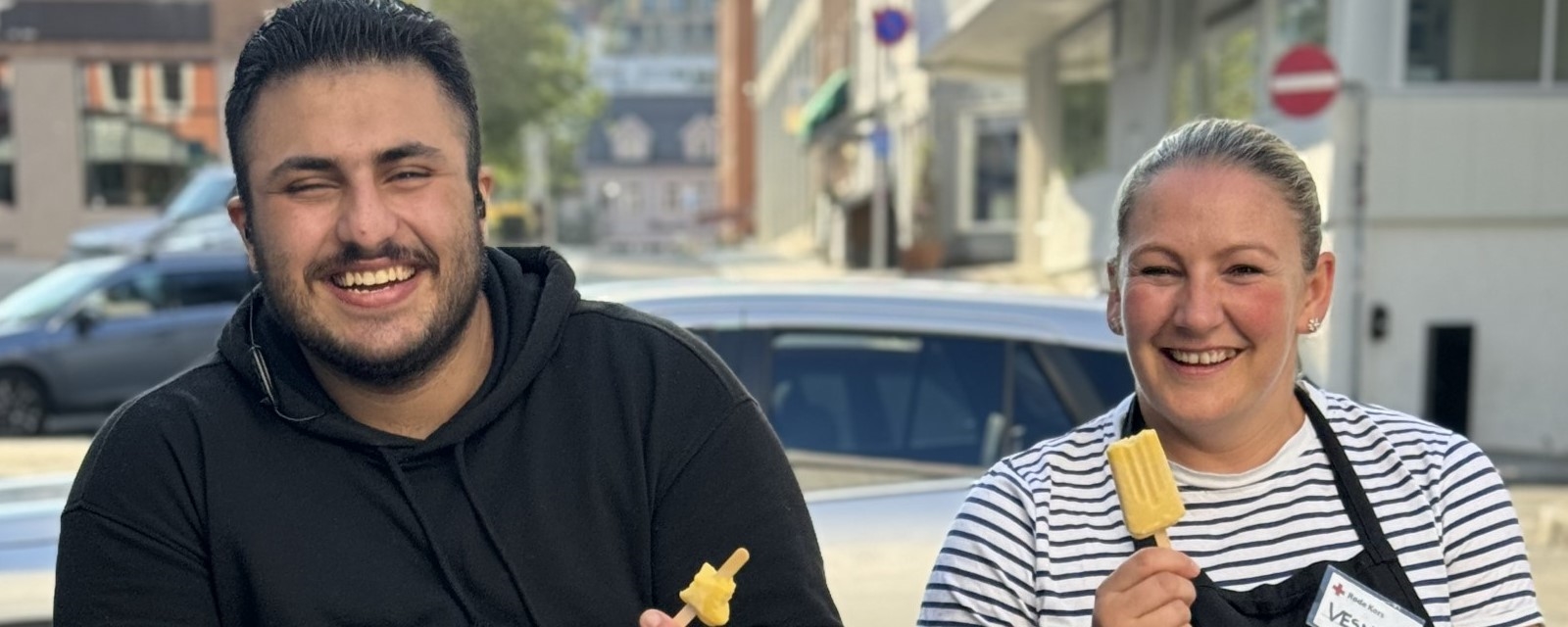 Bildet viser to personer som spiser is. De smiler og ler.