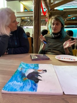 To mennesker sitter i en samtale rundt et bord.