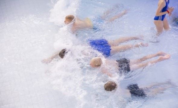 barn som svømmer i basseng