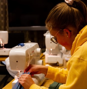 Bildet viser en person som syr på en symaskin.