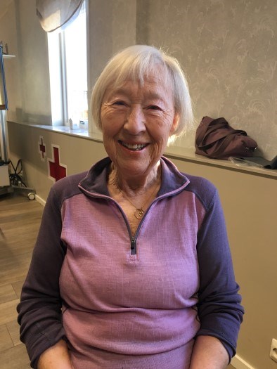 Bildet viser en dame på snart 90 år. Hun smiler vakkert til kamera, sittende på en stol.