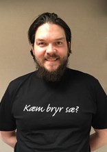Thomas Katten Gladsø ser mot kameraet og smiler, i en svart tskjorte med påskriften "Kæm bryr sæ?". 